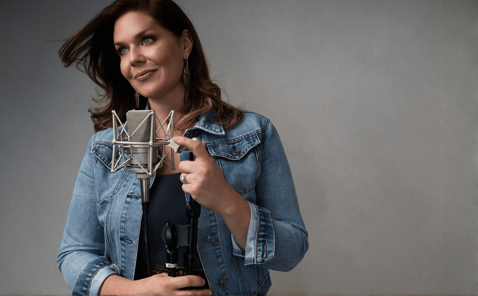Sarah Raines standing at her studio microphone